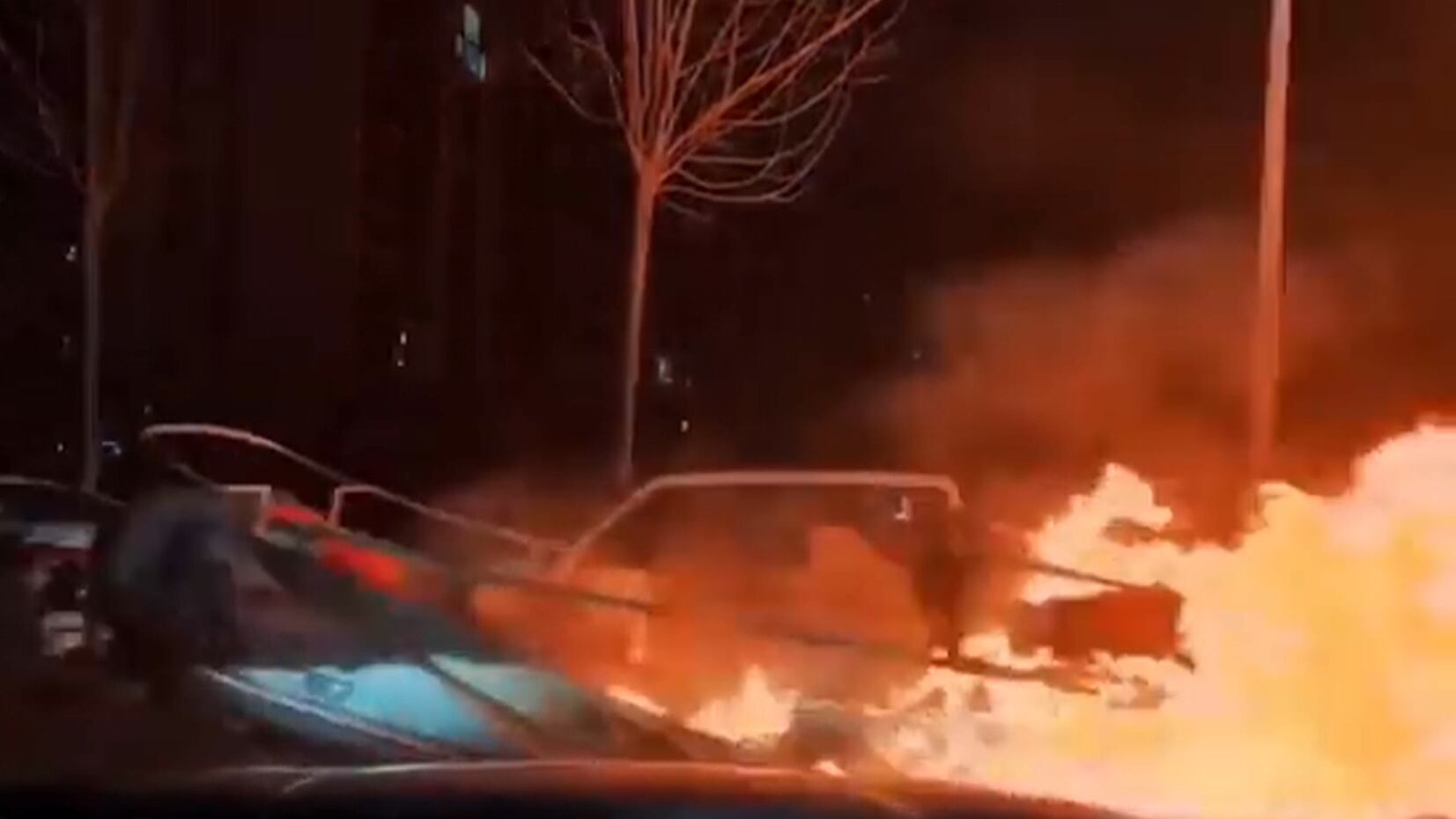 Motorista dirige trator com veículo incendiado no guincho